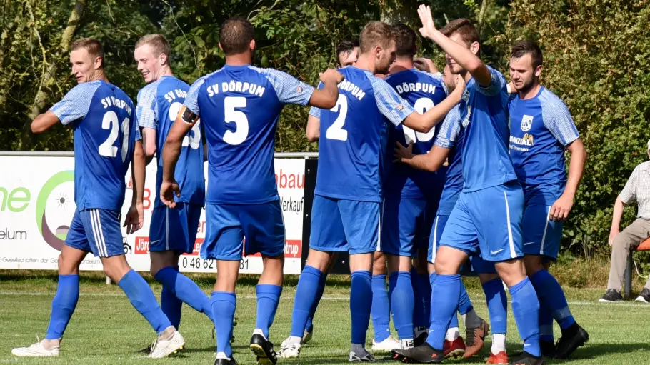 Die Dörpumer feiern das 2:0 und nehmen den Doppeltorschützen Thies Borchardt (19) in ihre Mitte. FOTO: WOLFGANG PUSTAL